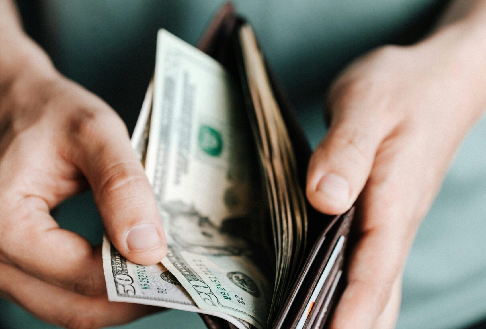 Close-up of hands holding a wallet with cash, depicting financial management.